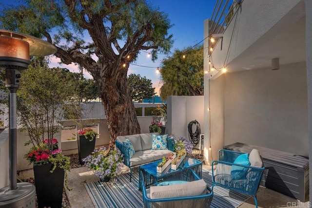 patio terrace at dusk featuring fence and an outdoor living space