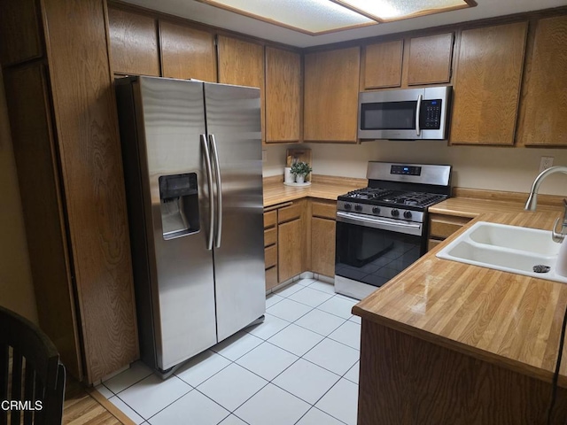 kitchen featuring sink, stainless steel appliances, kitchen peninsula, and light tile patterned flooring