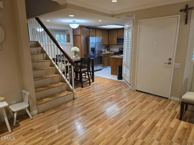 interior space featuring crown molding, appliances with stainless steel finishes, and light hardwood / wood-style floors