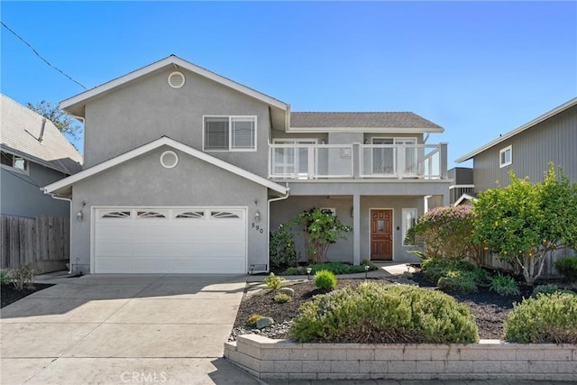 traditional-style home with stucco siding, a balcony, driveway, and fence