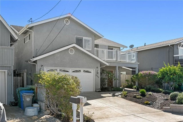 view of front of property with concrete driveway, a balcony, fence, and stucco siding