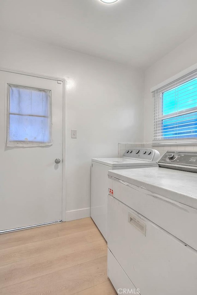 laundry room featuring baseboards, laundry area, independent washer and dryer, and light wood-style floors