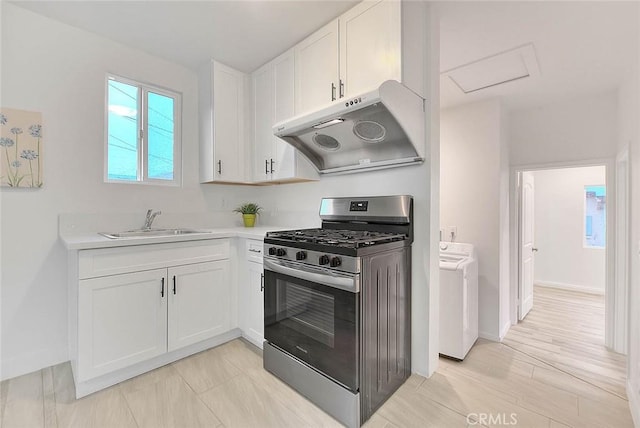 kitchen featuring stainless steel range with gas cooktop, light countertops, white cabinets, a sink, and under cabinet range hood