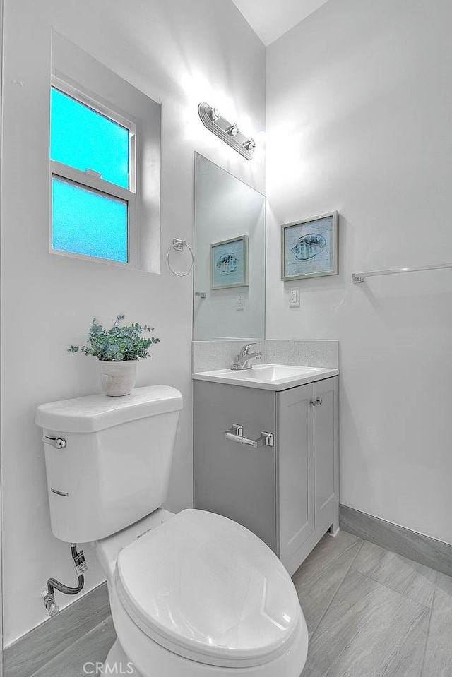 bathroom with baseboards, vanity, and toilet