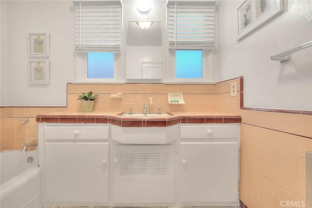 full bathroom with a garden tub, a sink, and tile walls