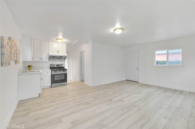 kitchen featuring light countertops, stainless steel range with gas cooktop, white cabinets, and under cabinet range hood