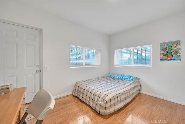 bedroom featuring baseboards, multiple windows, and light wood-style floors