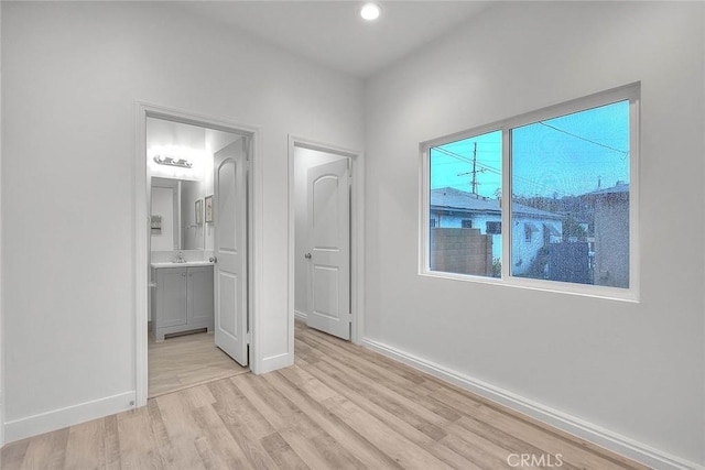 unfurnished bedroom featuring light wood-type flooring, ensuite bath, baseboards, and recessed lighting