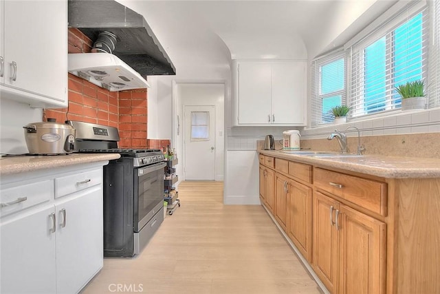 kitchen featuring extractor fan, a sink, white cabinetry, light countertops, and gas range