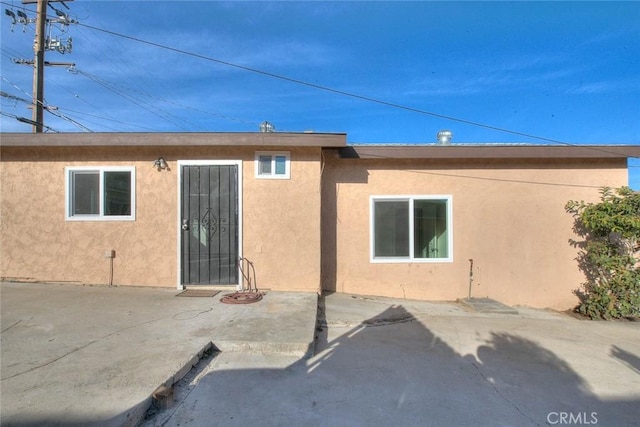 rear view of house with a patio and stucco siding