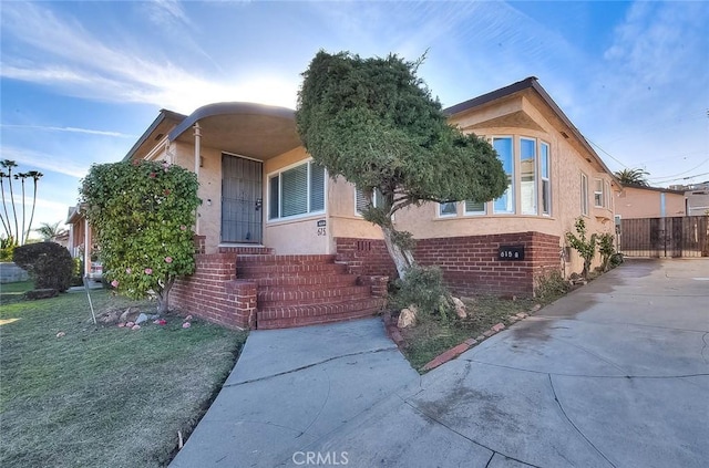 view of front of home with a front yard, fence, and stucco siding