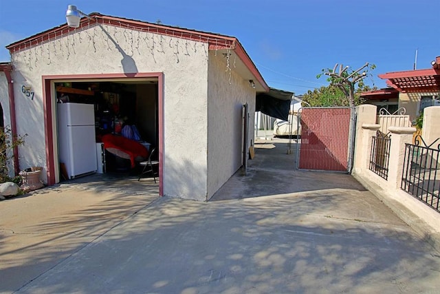 exterior space with driveway, fence, and freestanding refrigerator