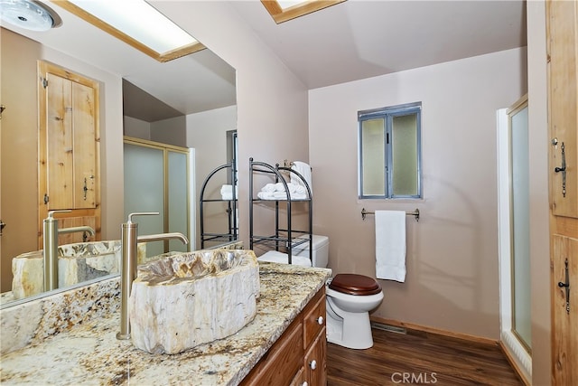 bathroom featuring vanity, wood-type flooring, a shower with door, and toilet