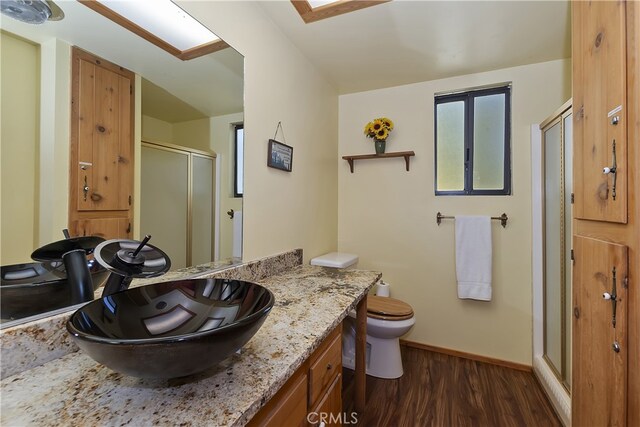 bathroom featuring hardwood / wood-style flooring, vanity, an enclosed shower, and toilet