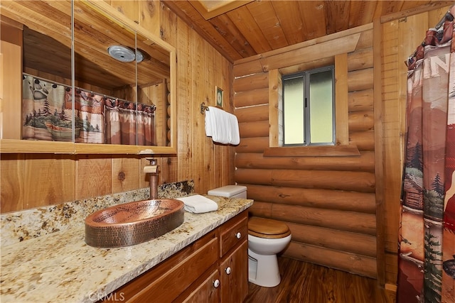 bathroom featuring toilet, wood-type flooring, wooden ceiling, vanity, and log walls