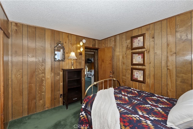 bedroom featuring wooden walls, a textured ceiling, and dark colored carpet