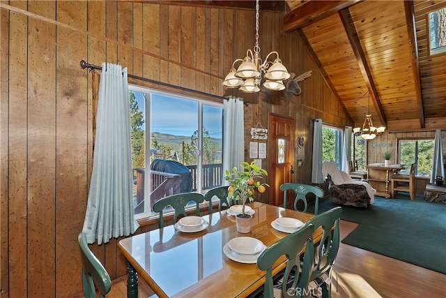 carpeted dining room with wood ceiling, beam ceiling, wooden walls, a notable chandelier, and a mountain view