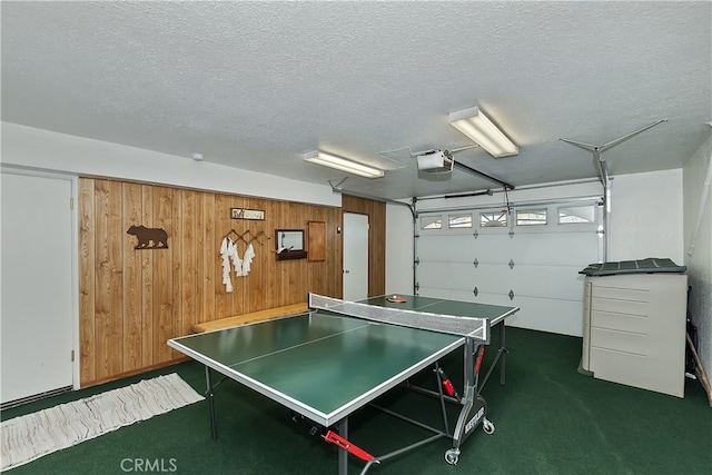 rec room with wood walls, a textured ceiling, and dark colored carpet