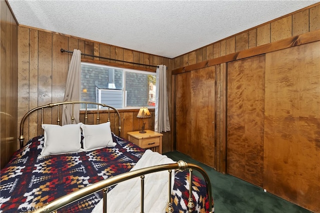 carpeted bedroom with a textured ceiling and wood walls