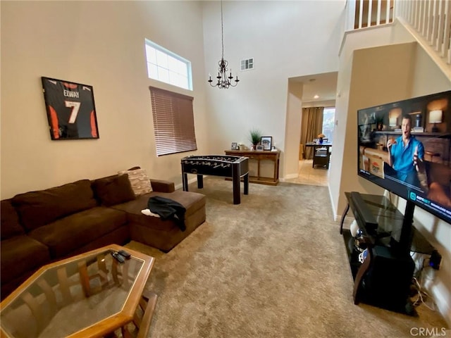 carpeted living room featuring baseboards, a high ceiling, visible vents, and a notable chandelier