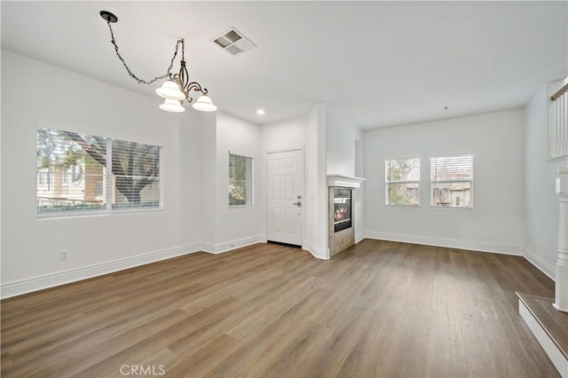 unfurnished living room with wood-type flooring and a chandelier