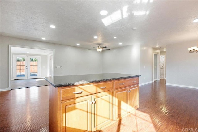 kitchen with recessed lighting, dark wood-type flooring, open floor plan, a kitchen island, and a textured ceiling