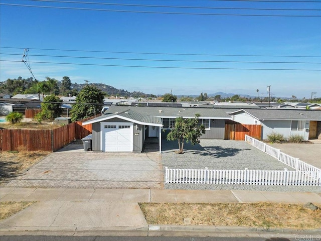 view of front of house featuring a fenced front yard, concrete driveway, an attached garage, and solar panels