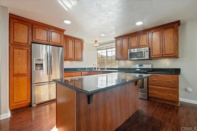 kitchen featuring stainless steel appliances, a center island, brown cabinets, and dark wood finished floors