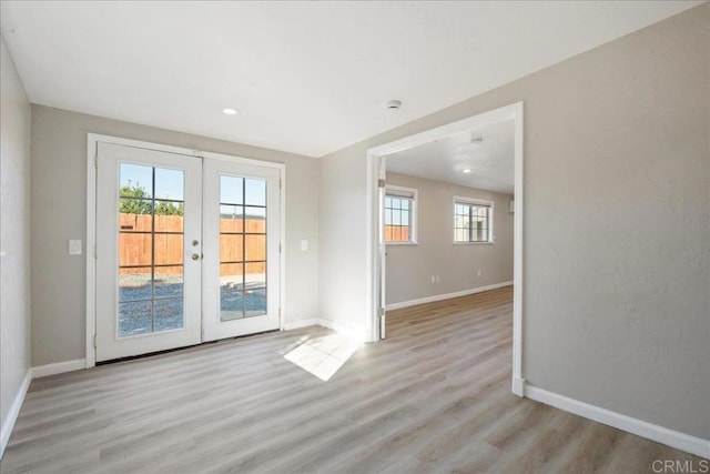 unfurnished room featuring baseboards, french doors, and light wood-style floors