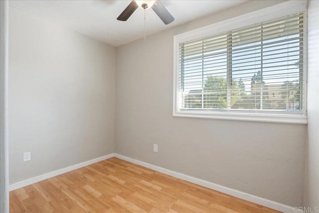 empty room featuring a ceiling fan, baseboards, and wood finished floors