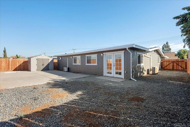 back of property featuring a storage unit, a fenced backyard, french doors, an outdoor structure, and a patio area