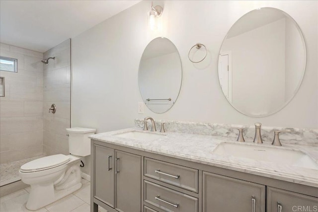 bathroom with a sink, toilet, double vanity, and a tile shower