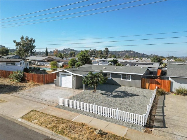 ranch-style house with a fenced front yard, a garage, and driveway