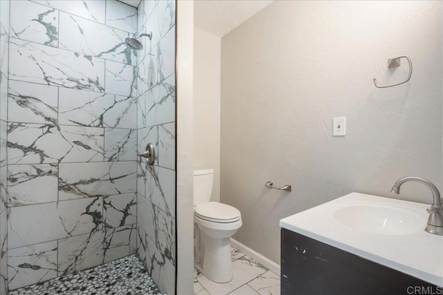 bathroom with vanity, baseboards, tiled shower, toilet, and marble finish floor