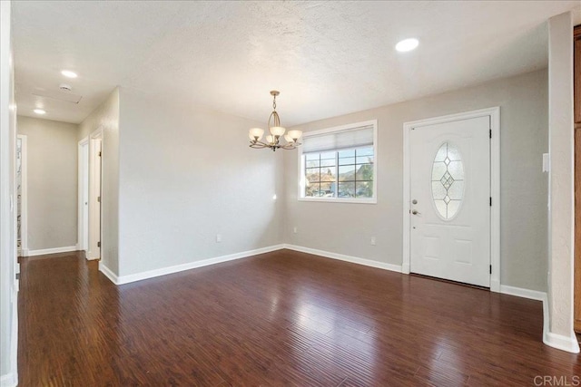 entryway featuring dark wood-style floors, a notable chandelier, a textured ceiling, and baseboards