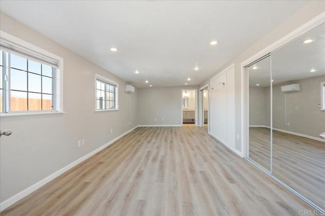 interior space featuring a wall unit AC, recessed lighting, light wood-style floors, and baseboards