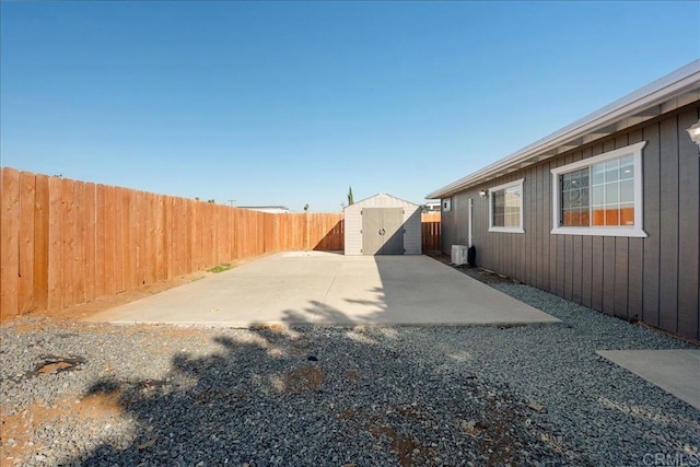 view of yard featuring a patio, a shed, a fenced backyard, and an outbuilding