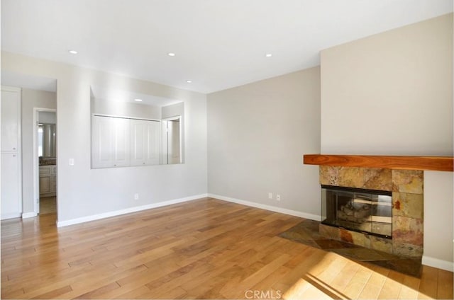 unfurnished living room featuring light hardwood / wood-style floors and a tile fireplace