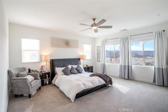 bedroom with light carpet, a mountain view, and ceiling fan