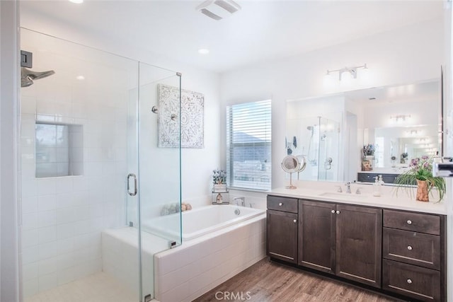 bathroom with wood-type flooring, independent shower and bath, and vanity