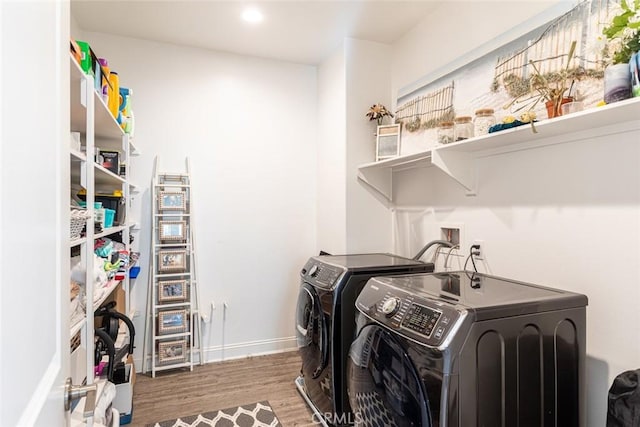 clothes washing area featuring washing machine and clothes dryer and wood-type flooring