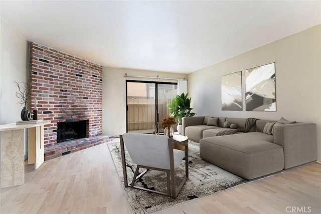 living room featuring a brick fireplace and light wood-type flooring