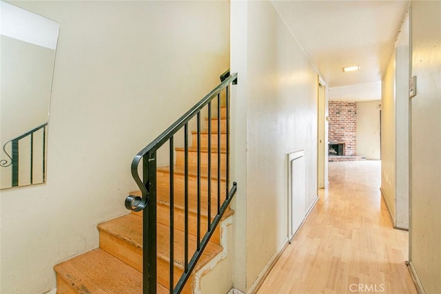 stairs featuring hardwood / wood-style flooring and a fireplace