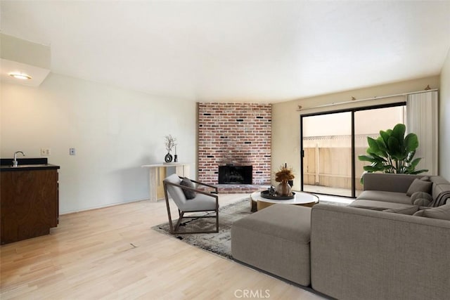 living room with a brick fireplace and light wood-type flooring