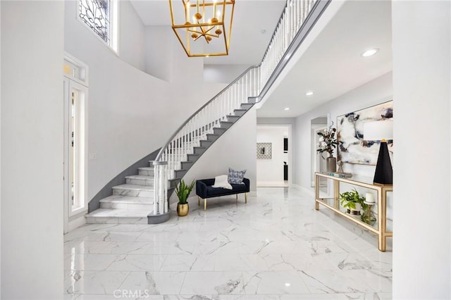 foyer featuring marble finish floor, stairway, and a towering ceiling