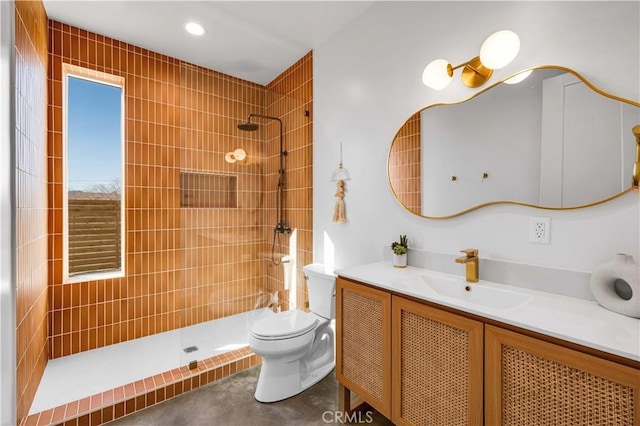 bathroom with vanity, toilet, and tiled shower