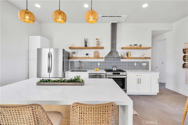 kitchen with appliances with stainless steel finishes, decorative light fixtures, white cabinets, decorative backsplash, and wall chimney exhaust hood