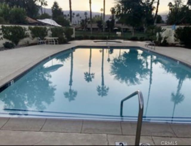 pool at dusk with a patio area