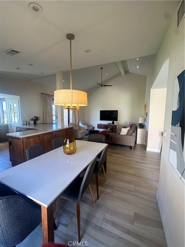 dining space with lofted ceiling with beams and light wood-type flooring