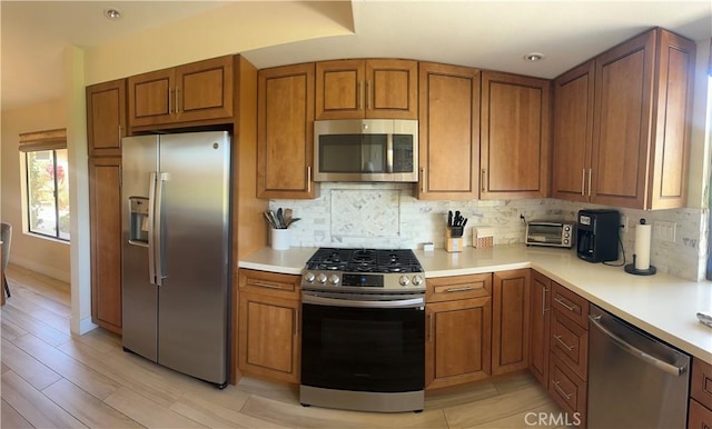 kitchen featuring tasteful backsplash, stainless steel appliances, and light wood-type flooring